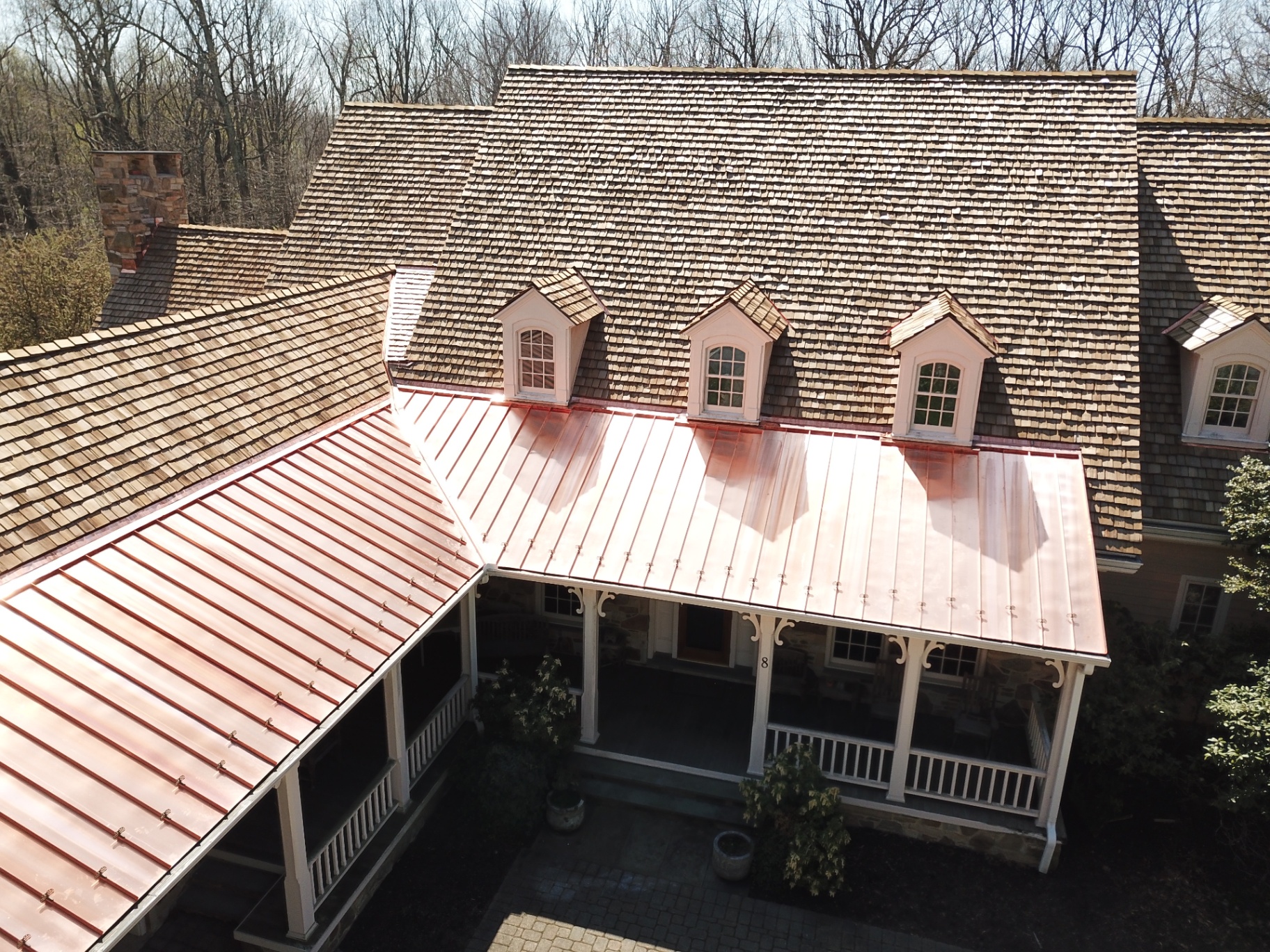 Cedar shake roof with copper standing seam porch roof