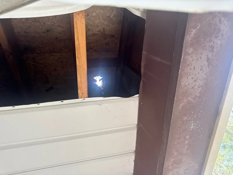 Daylight visible through the roof deck from beneath the torn soffit