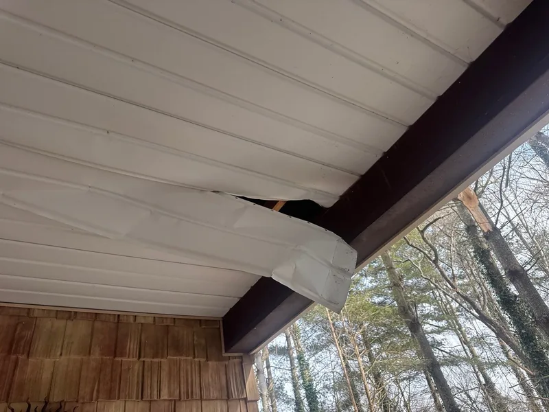 Soffit panel torn loose beneath the porch beam